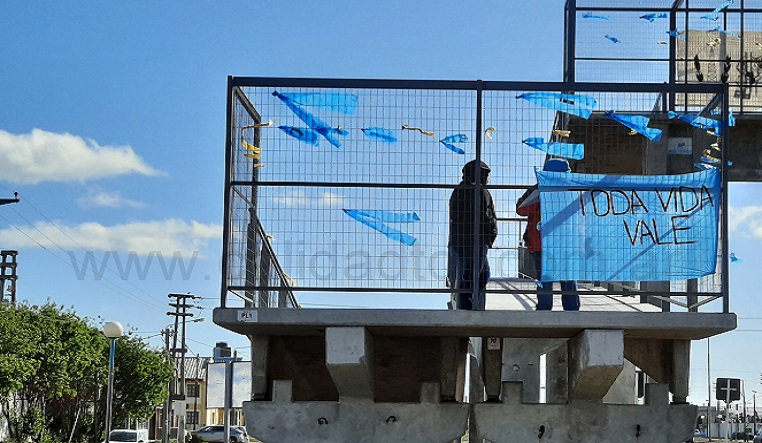 La demora en el arribo del Presidente de la Nacin, dio tiempo para que un grupo de personas se organizaran en la tarea de encintar con trozos de la tela de color celeste el puente peatonal ubicado frente a la estacin de GNC.